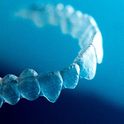 Closeup of clear aligner against blue background