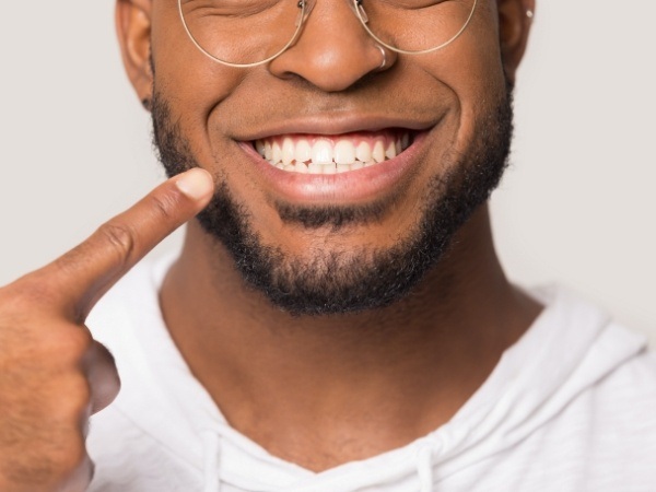 Person pointing to healthy smile after scaling and root planing gum disease treatment