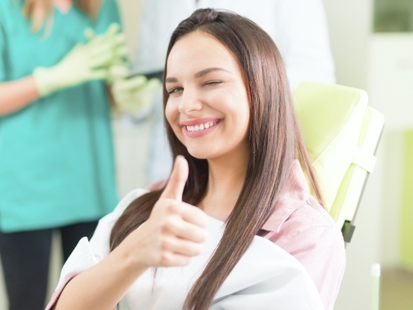 Woman in dental chair giving thumbs up