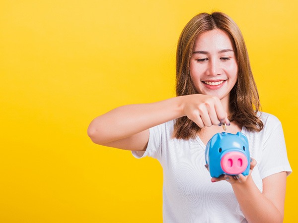 woman putting a coin in a piggy bank