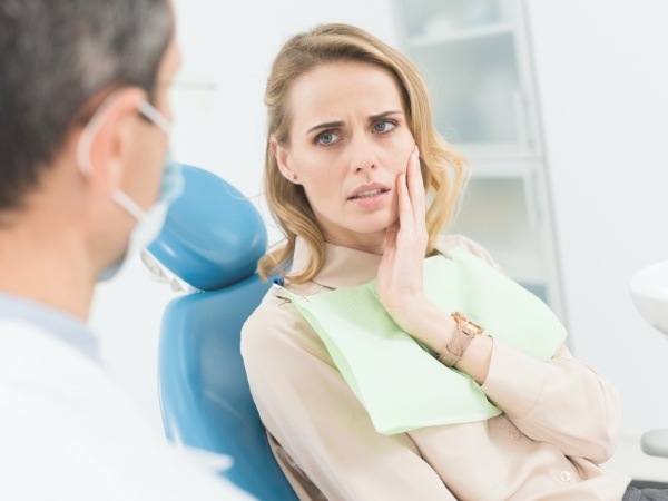 Woman holding cheek in pain before emergency dentistry treatment