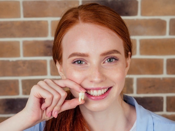 Woman holding a tooth after extraction