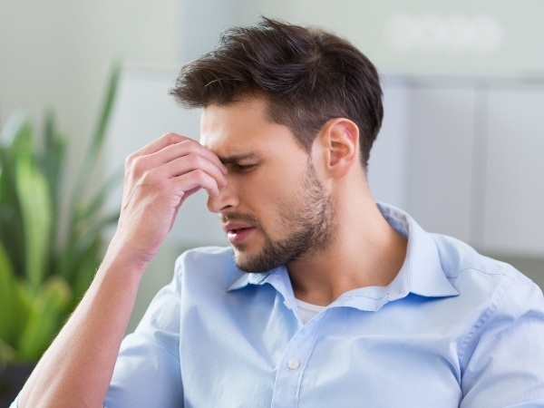 Person with headache holding the bridge of their nose