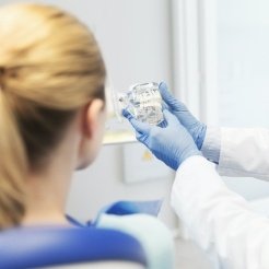 Dentist using smile model to explain dental implant surgery