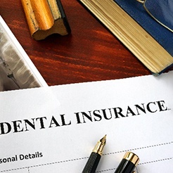 Dental insurance paperwork lying on desk with supplies