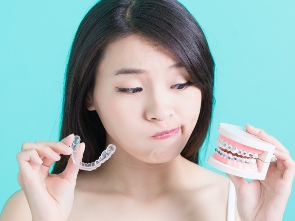 Woman comparing Invisalign and metal braces