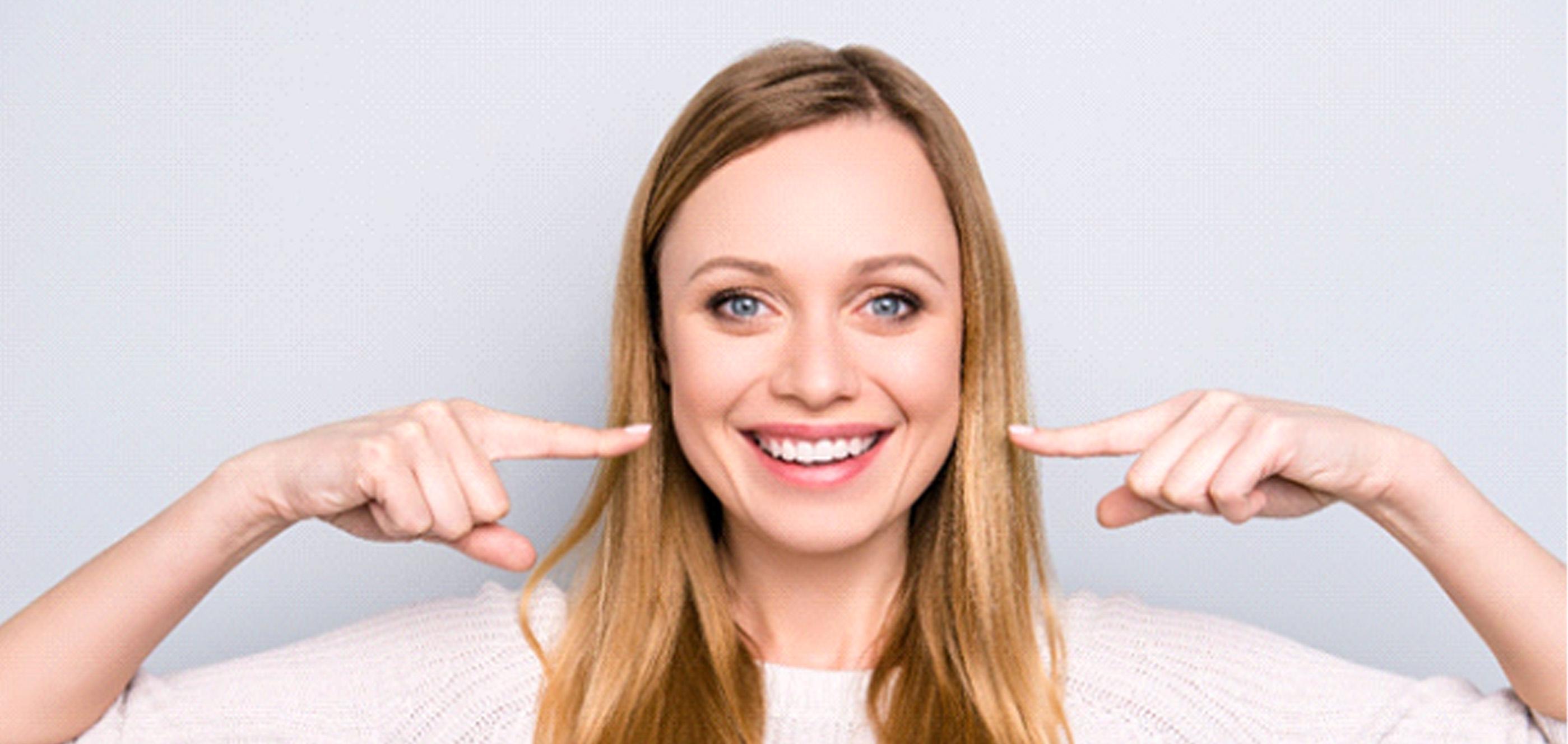 Happy woman pointing at her beautiful smile