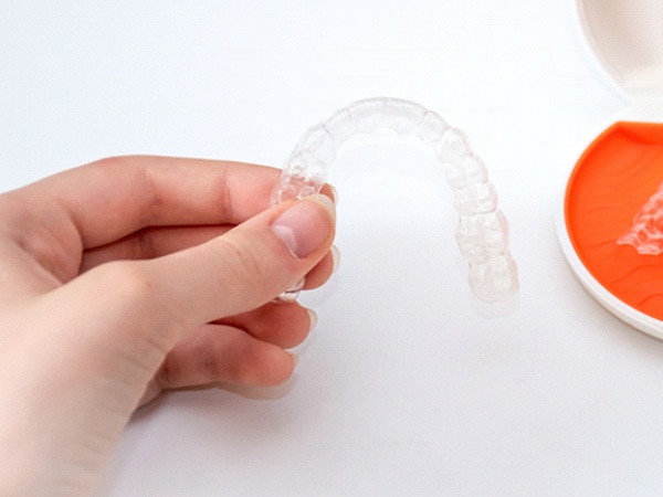 Person’s hand holding Vivera orthodontic retainer