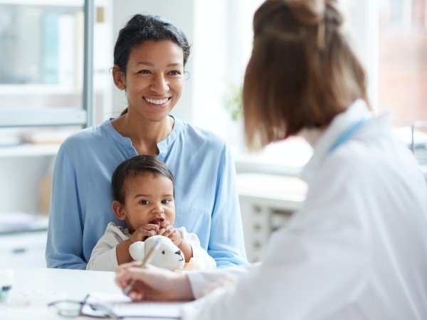 Children's dentist talking to young dental patient and parent