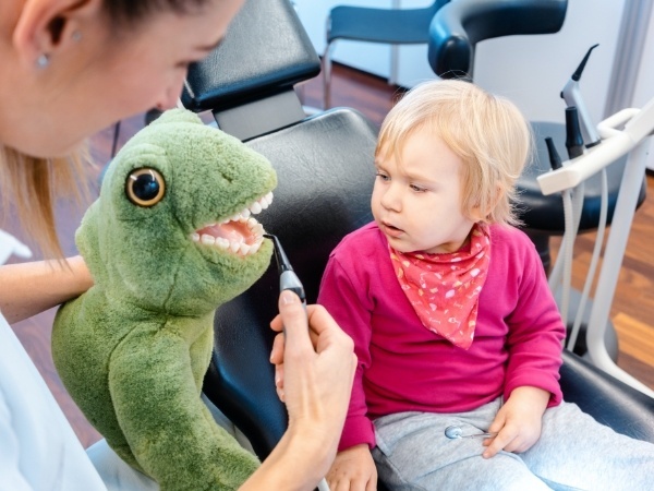 Dentist teaching child to brush teeth