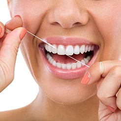 Closeup of patient smiling while flossing her teeth