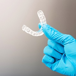 Dentist holding clear mouthguard with blue gloves