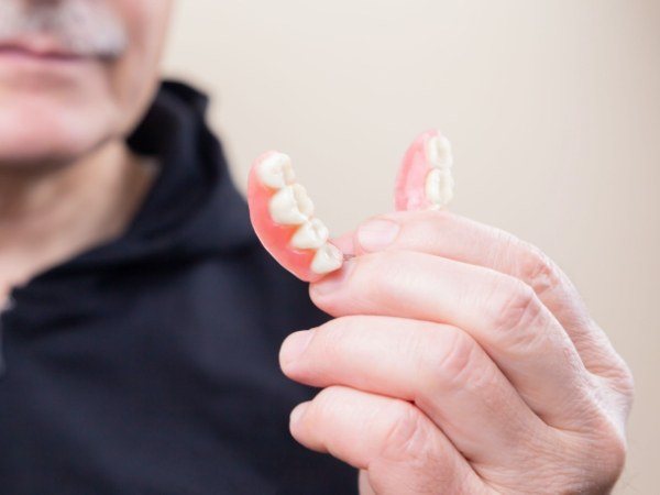 Hand holding full denture