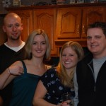 Four people smiling at a party in the kitchen