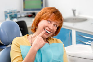 senior woman pointing to beautiful smile 