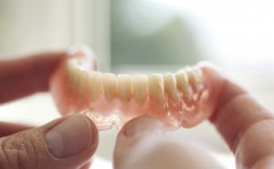 person holding their dentures