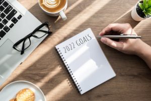 Notebook with New Year’s resolutions for 2022 sitting on desk